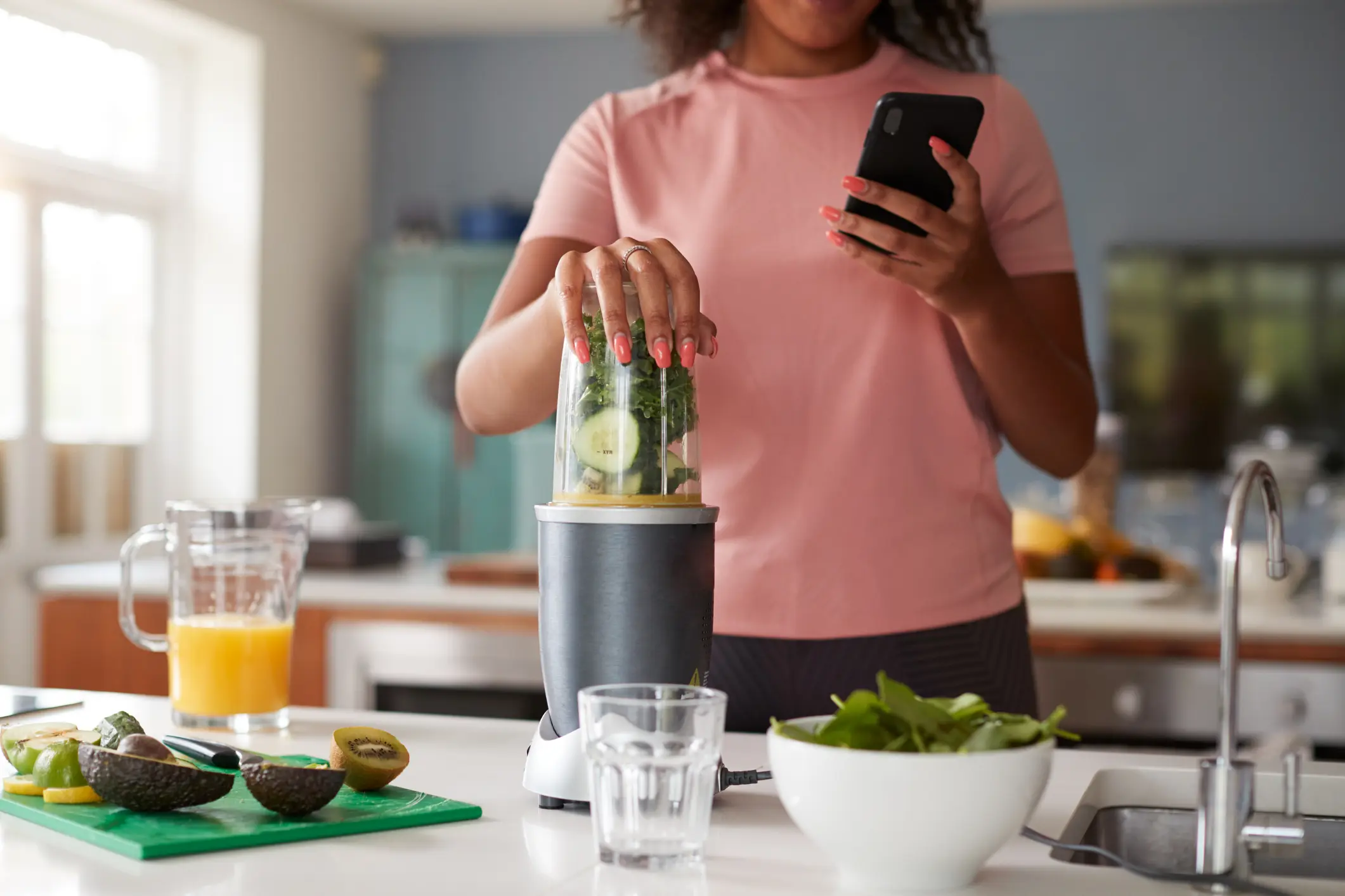Woman blending green smoothie in kitchen