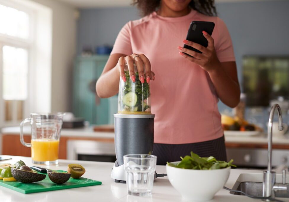 Woman blending green smoothie in kitchen